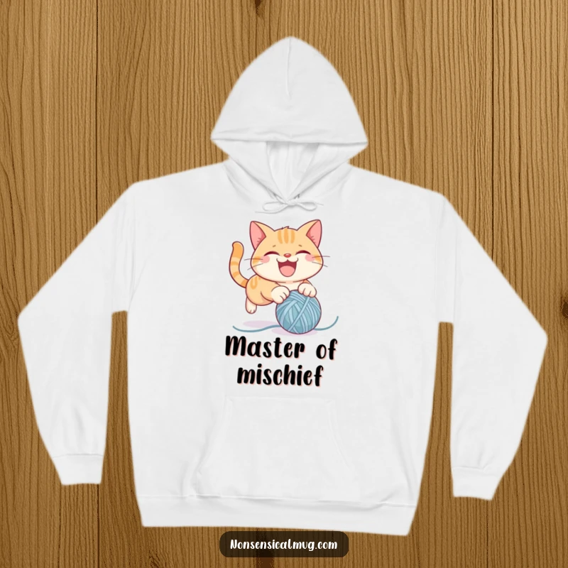 Funny hoodie showcasing a mischievous cat character energetically pouncing on a ball of yarn, ideal for cat lovers and comfort seekers.