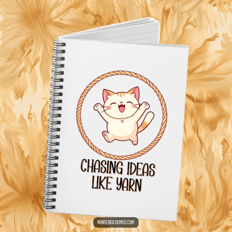 Funny round cat joyfully leaping through a hoop of yarn on a notebook, inspiring creativity and playful writing.