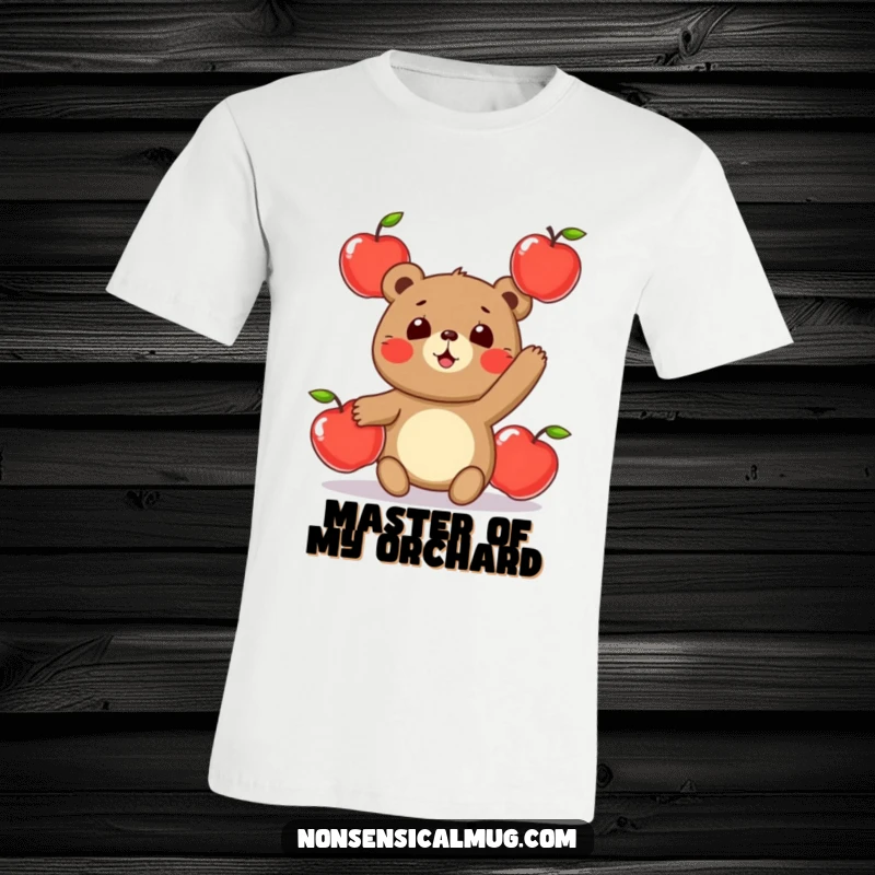 Funny t-shirt graphic of a round, happy bear character attempting to juggle three shiny apples with a focused, yet comical, expression.